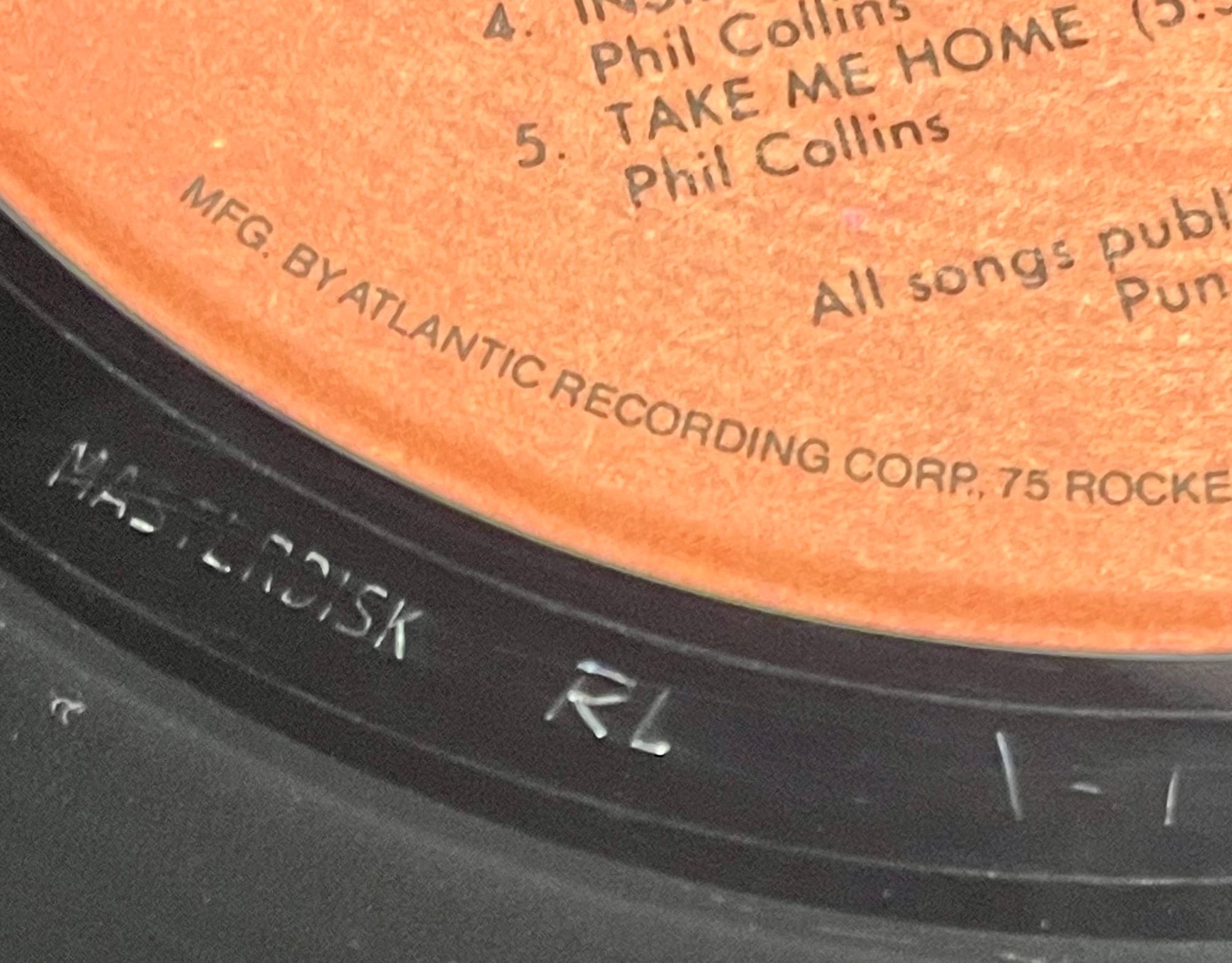 Detailed macro photography showing mastering engineer initials etched in vinyl deadwax, with "RL" clearly visible